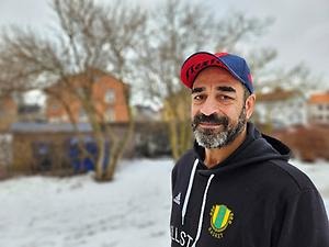 Tränaren Jens står utomhus framför ett tegelhus.