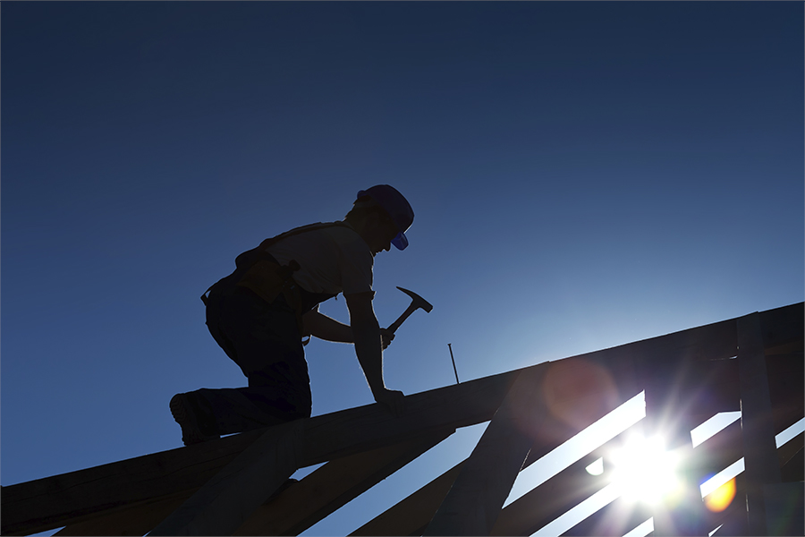 Byggnadsarbetare som snickrar på taket till ett kommande hus.