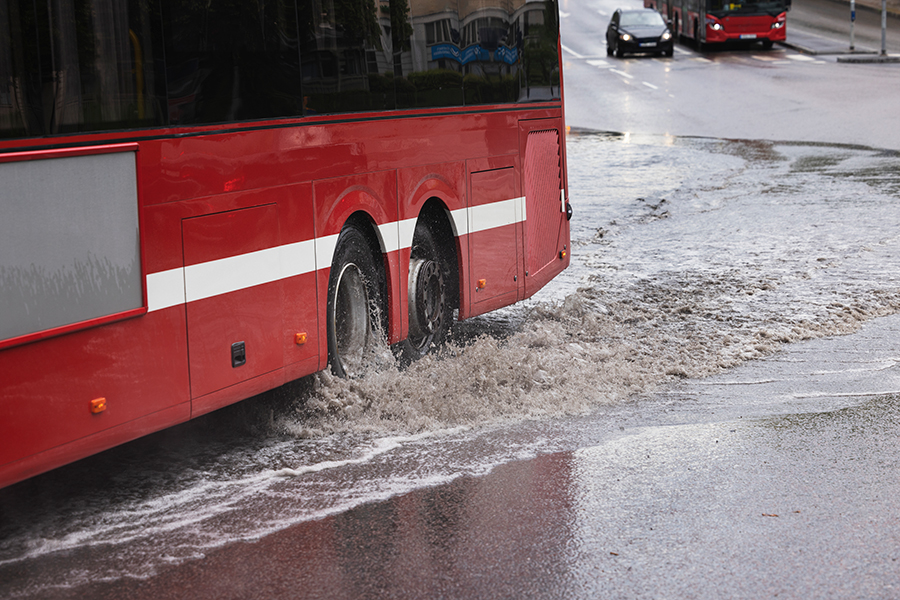 Buss kör genom stor vattenpöl efter oväder