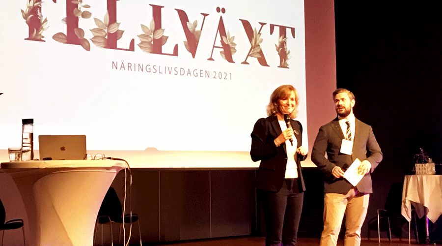 Camilla König Ekegren från Väsby Promotion och Oskar Weinmar kommunstyrelsens ordförande står på en scen.