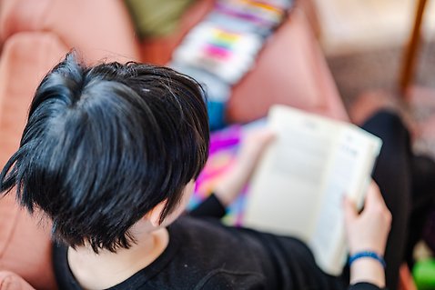 Ett barn sitter i en soffa och läser en bok