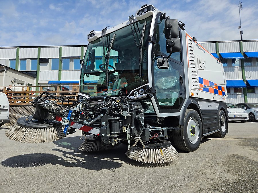 Vit sopsugmaskin med borstar framtill. 