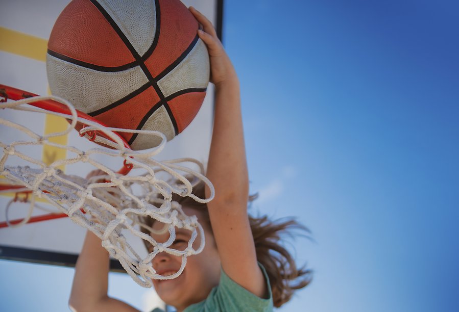 Ett barn träffar basketkorgen med sin basketboll. 
