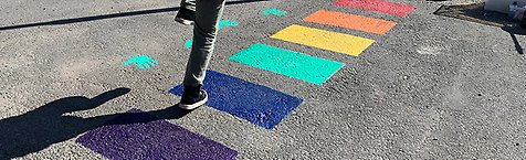 Ett barn hoppar mellan de olika målade färgrutorna på en förskolegård. 