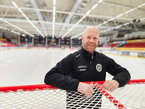 Man vid hockeymål i ishall.