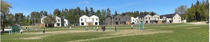 Bild på barn som spelar fotboll på fotbollsplan och i bakgrunden syns nybyggda bostäder i Wijk Oppgård